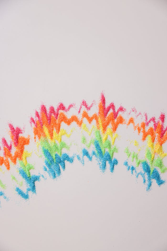 Colorful glitter art with rainbow zigzags on a white surface, showcasing creativity and color.